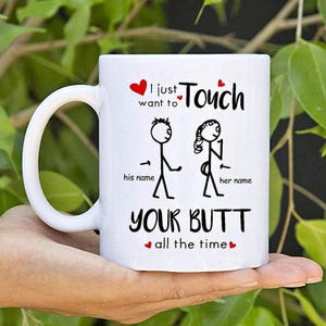 Pode incluir: Caneca de cerâmica branca com um gráfico preto e vermelho. A caneca apresenta bonecos de palito e o texto "I just want to Touch YOUR BUTT all the time."