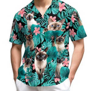 May include: Short-sleeved button-down shirt featuring a vibrant print of Siamese cats amidst tropical foliage and pink flowers. The shirt has a black background with teal leaves and a classic collar.