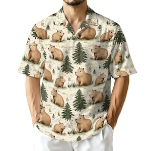 May include: Short-sleeved button-down shirt with a repeating pattern of capybaras, evergreen trees, and foliage on a cream background. The capybaras are depicted in various poses, adding visual interest to the design.
