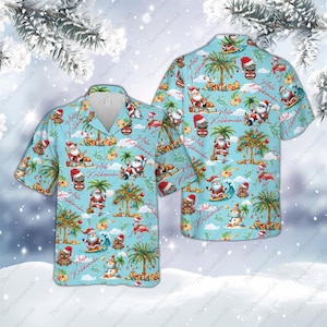 May include: Two short-sleeved Hawaiian shirts with a light blue background. The shirts feature a tropical Christmas theme with Santa Claus, palm trees, and the text "Aloha Kalikimaka".
