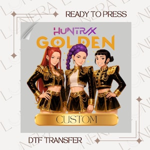 May include: DTF transfer featuring three anime-style women in black and gold military-inspired outfits. The text "HUNTR/X GOLDEN" and "CUSTOM" are displayed. The words "READY TO PRESS" and "DTF TRANSFER" are also visible.