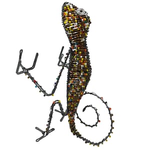 May include: A handcrafted lizard sculpture made of wire and colorful beads. The lizard has a curled tail and outstretched arms. The body is a mix of brown, yellow, orange, and white beads. The eyes are silver.