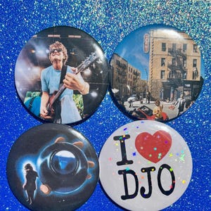 May include: Four circular badges with various designs. One shows a person playing guitar, another a city street, a third a dark graphic, and the last says "I DJO" with a red heart.