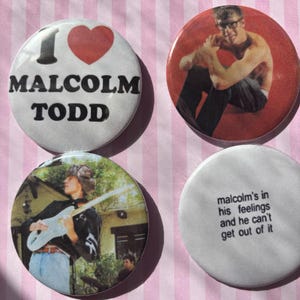 May include: Four round buttons with images and text. One button says "I ❤️ MALCOLM TODD" with a red heart. Another shows a man in glasses. A third shows a man playing guitar. The last says "malcolm's in his feelings and he can't get out of it."