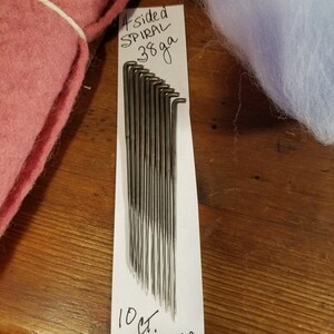 May include: A white card with black handwritten text that reads "4 sided SPIRAL 36ga 10 ct. SPIRAL STAR".  The card is showing a set of 10 silver metal spiral knitting needles.