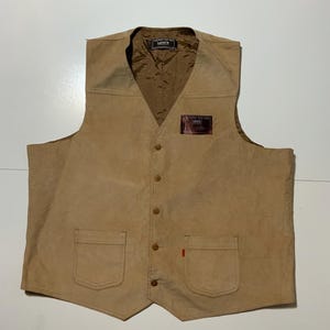 May include: Tan Levi's vest with a button-up front, two front pockets, and a small red tag. The vest has a V-neck and a brown interior lining. The Levi's logo is visible on a small patch.