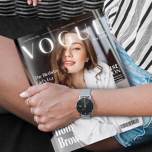 Könnte beinhalten: Eine Person hält eine Ausgabe des Vogue-Magazins mit einer Frau auf dem Cover. Der Titel des Magazins ist in großen weißen Buchstaben gehalten. Am Handgelenk der Person befindet sich eine silberne Uhr mit schwarzem Zifferblatt. Der Text des Magazins lautet "Happy Birthday Ashley" und "The Birthday Girl's Era."