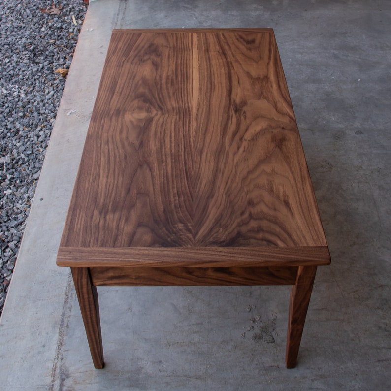 May include: A dark brown wooden coffee table with a rectangular top and four legs. The table has a natural wood grain pattern.