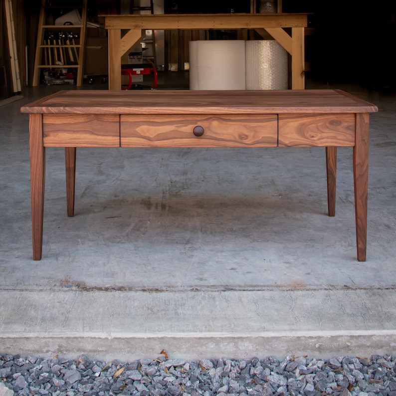 May include: A wooden table with a single drawer and a dark brown finish. The table has four legs and a rectangular top.