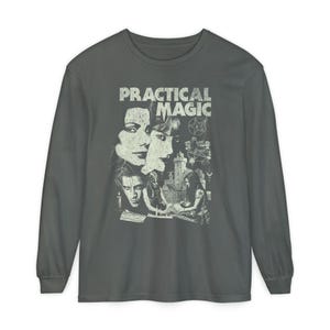Könnte beinhalten: Ein graues Langarmshirt mit einem Grafikdesign aus dem Film "Practical Magic". Die Grafik zeigt den Filmtitel und Bilder der Hauptfiguren. Das Shirt ist aus einem weichen Material gefertigt.