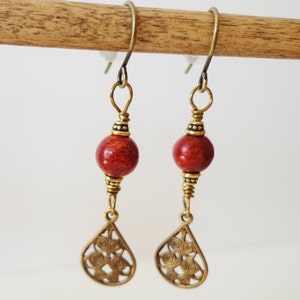 May include: A pair of dangle earrings with red coral beads and gold filigree teardrop charms.