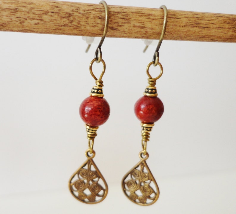 May include: A pair of dangle earrings with red coral beads and gold filigree teardrop charms.