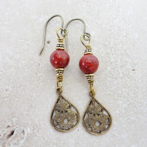 May include: A pair of dangle earrings with red coral beads and gold filigree teardrop charms.