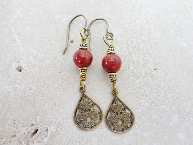 May include: A pair of dangle earrings with red coral beads and gold filigree teardrop charms.