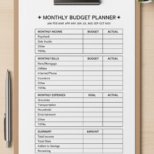May include: A clipboard with a printed monthly budget planner. The planner includes sections for income, bills, and expenses, with spaces for budget, actual, and goal amounts. A pen and a small potted plant are also visible.