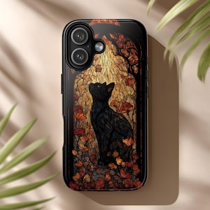 May include: A black smartphone case featuring a stained glass style illustration of a black cat sitting amidst orange and red autumn leaves. The cat is looking upward within an arched frame, set against a warm, glowing golden background.