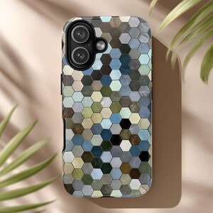 Könnte beinhalten: Eine Smartphone-Hülle mit einem geometrischen Muster aus kleinen, mehrfarbigen Sechsecken. Die Hülle hat einen Kameraausschnitt und einen schwarzen Rand. Die Farbpalette umfasst Blau-, Grün-, Braun- und Grautöne und erzeugt ein mosaikartiges Design.