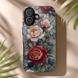 May include: A phone case featuring a stained-glass design with roses in shades of red, cream, and white. The case has a glossy finish and a dark gray background with a mosaic pattern. Green leaves and stems complete the floral design.