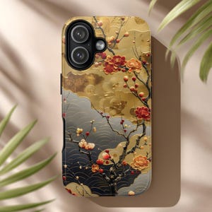 May include: A phone case featuring a gold, gray, and black floral design. The case has a glossy finish and a detailed illustration of blossoming branches with red and peach-colored flowers. The design is reminiscent of traditional Asian art.