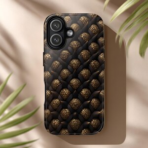 May include: A smartphone case with a textured design featuring a repeating pattern of dark brown and gold elements. The case has a glossy finish and a camera cutout.