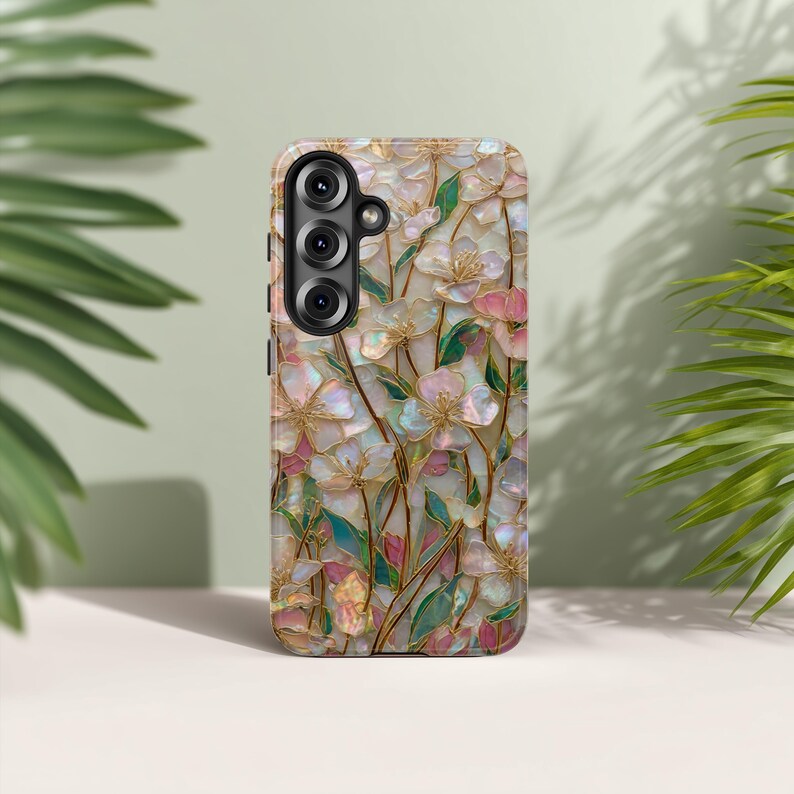 May include: A rectangular mobile phone case featuring a decorative inlay pattern of iridescent, mother-of-pearl style flower petals in shades of white, soft pink, and green, accented by thin gold-toned metallic lines throughout the floral design.