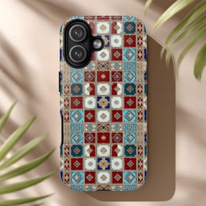May include: A decorative phone case featuring a mosaic tile design. The case has a repeating pattern of red, blue, white, and gold squares. The phone case has a black border and a camera cutout.