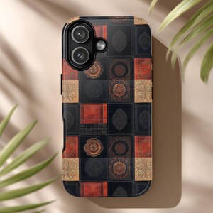 Op de afbeelding: Een telefoonhoesje met een geometrisch patroon. De hoes heeft een patchwork-ontwerp met zwarte, rode en gouden vierkanten. De vierkanten zijn versierd met sierlijke, cirkelvormige en bloemmotieven. De hoes heeft een glanzende afwerking en een camera-uitsparing.