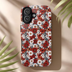 Peut inclure: Coque de téléphone à motifs floraux, avec des coquelicots rouges et des marguerites blanches sur fond sombre. La coque a une finition brillante et un module caméra noir. Le design allie botanique et modernité.
