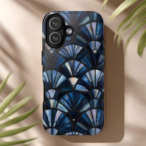 May include: A smartphone case with a blue and white Art Deco fan pattern. The case has a glossy finish and features a dual-lens camera cutout. Small, clear embellishments are placed on the case.