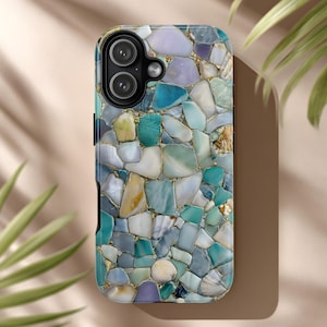 May include: A smartphone case with a mosaic design. The case features a pattern of irregular, colorful stones in shades of blue, green, and white, with gold-colored accents. Small seashells are embedded within the design, adding a coastal theme.