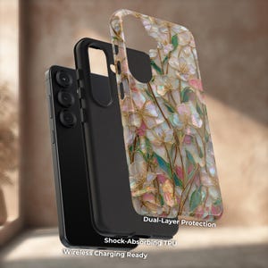 May include: A smartphone case featuring a floral pattern with iridescent pink, white, and green petals outlined in gold. The case includes a black shock-absorbing TPU inner layer, dual-layer protection, and is wireless charging ready.