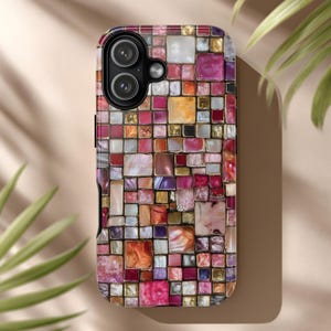 May include: A colorful phone case with a mosaic design. The case features a pattern of small, square tiles in shades of pink, purple, orange, and gold. The camera lenses are visible at the top. The case is designed to protect the phone.