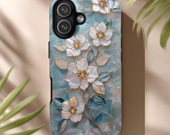 May include: A smartphone case featuring a floral design. The case has a light blue mosaic background with white flowers and gold accents. The flowers have a pearlescent sheen, and the leaves are a muted green.