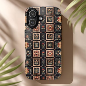 Puede incluir: Funda de teléfono negra con un estampado floral en rojo, amarillo y blanco. El diseño presenta un motivo cuadrado repetitivo con flores y hojas estilizadas. La funda tiene un acabado brillante y un recorte para la cámara.