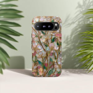 May include: A smartphone case featuring an iridescent, mother-of-pearl style floral pattern with delicate gold-toned outlines. The design displays light pink and white flower petals interspersed with green leaves and thin, winding stems across the surface.