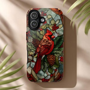 May include: A smartphone case featuring a stained glass style illustration of a bright red cardinal bird perched among green pine needles, brown pinecones, and clusters of red berries against a background of muted green and white glass panes.
