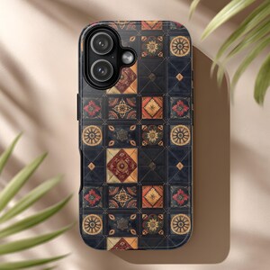 May include: A smartphone case with a decorative patchwork design. The case features a pattern of squares in dark blue, red, orange, and gold. The design includes floral and geometric motifs, creating a vintage or bohemian aesthetic.