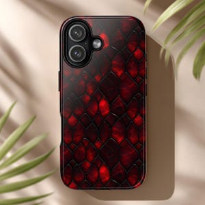 Puede incluir: Una funda para smartphone con un diseño de piel de serpiente roja y negra. La funda tiene un acabado brillante y un recorte para la cámara en la parte superior. El diseño presenta un patrón repetitivo en tonos rojos y negros.