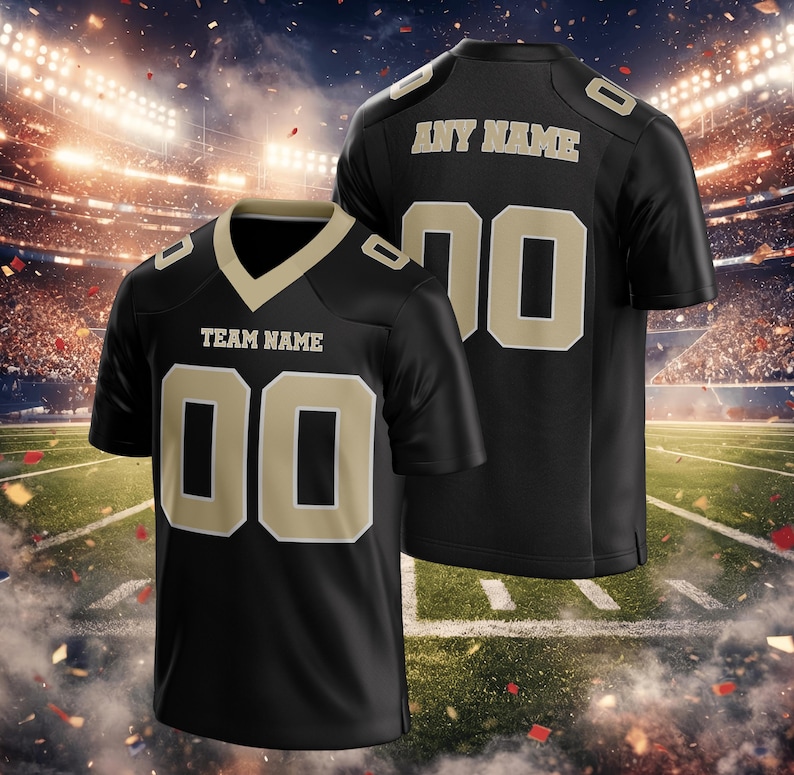 Puede incluir: Camiseta de f&uacute;tbol negra con detalles dorados. La camiseta muestra "TEAM NAME" y el n&uacute;mero "00" en la parte delantera. La parte trasera muestra "ANY NAME" y el n&uacute;mero "70". La imagen muestra la camiseta sobre un fondo de estadio.