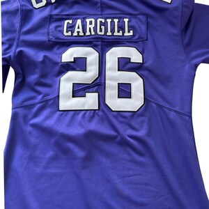 Puede incluir: Una camiseta de f&uacute;tbol morada con letras y n&uacute;meros blancos. El nombre "CARGILL" se muestra encima del n&uacute;mero "26" en la espalda. El n&uacute;mero "6" es visible en el hombro.