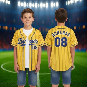 May include: Two children wearing yellow baseball jerseys with blue pinstripes and the word "Bananas" on the front and back. The number "08" is on the front and back of the jersey. The children are wearing blue denim shorts.