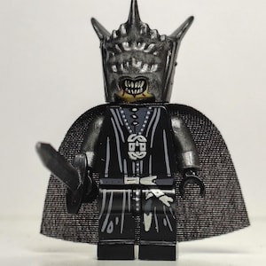 Può includere: Una minifigure Lego del Re Stregone di Angmar, un personaggio de Il Signore degli Anelli. La figura è prevalentemente nera con dettagli argentati, tra cui un elmo con spuntoni, un mantello e una spada. La figura ha un'espressione minacciosa.