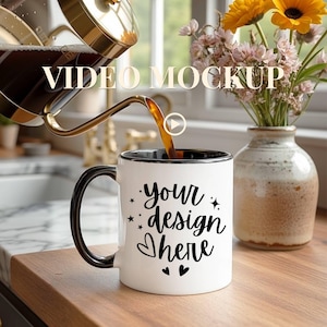 May include: A white coffee mug with a black rim and handle is being filled with coffee. The mug has the text "your design here" in a script font. A vase of flowers sits in the background. The words "VIDEO MOCKUP" are at the top.
