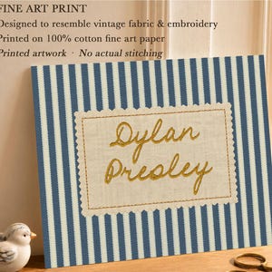 May include: A fine art print featuring a blue and white vertical striped pattern with a central rectangular beige patch. The patch has a scalloped edge and displays the name Dylan Presley in gold script. Text on the print reads: FINE ART PRINT, Designed to resemble vintage fabric & embroidery, Printed on 100% cotton fine art paper, Printed artwork &middot; No actual stitching.