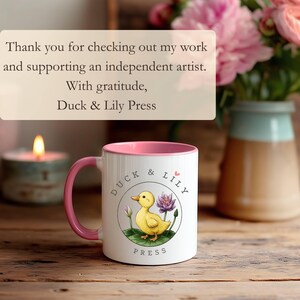 May include: White ceramic mug with a pink interior and handle. The mug features a yellow duck illustration with a purple water lily and the text "Duck & Lily Press". The image also includes the text "Thank you for checking out my work and supporting an independent artist."