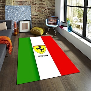 Puede incluir: Una alfombra rectangular con un diseño verde, blanco y rojo, con el logotipo de Ferrari. La alfombra tiene una franja verde a la izquierda, una franja blanca en el medio con el logotipo y una franja roja a la derecha. El logotipo de Ferrari es un escudo amarillo con un caballo negro.