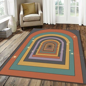 May include: A rectangular area rug with a retro design. The rug features a series of concentric archways in shades of orange, teal, yellow, purple, and gray. The rug is placed on a wooden floor.