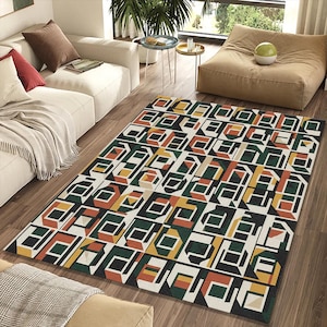 May include: A rectangular area rug with a geometric pattern in black, white, green, orange, and yellow. The rug features a repeating design of three-dimensional shapes, creating a modern and abstract look. The rug is placed on a hardwood floor.