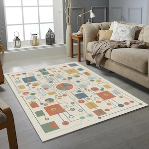 May include: A rectangular area rug with a cream background and a colorful geometric design. The design features squares, circles, and lines in shades of blue, orange, yellow, and green. The rug is placed in a living room setting.