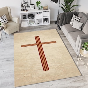 Puede incluir: Alfombra rectangular beige con un diseño de cruz grande. La cruz está compuesta por rayas burdeos y doradas. La alfombra está colocada sobre un suelo claro. Las dimensiones de la alfombra no son visibles.